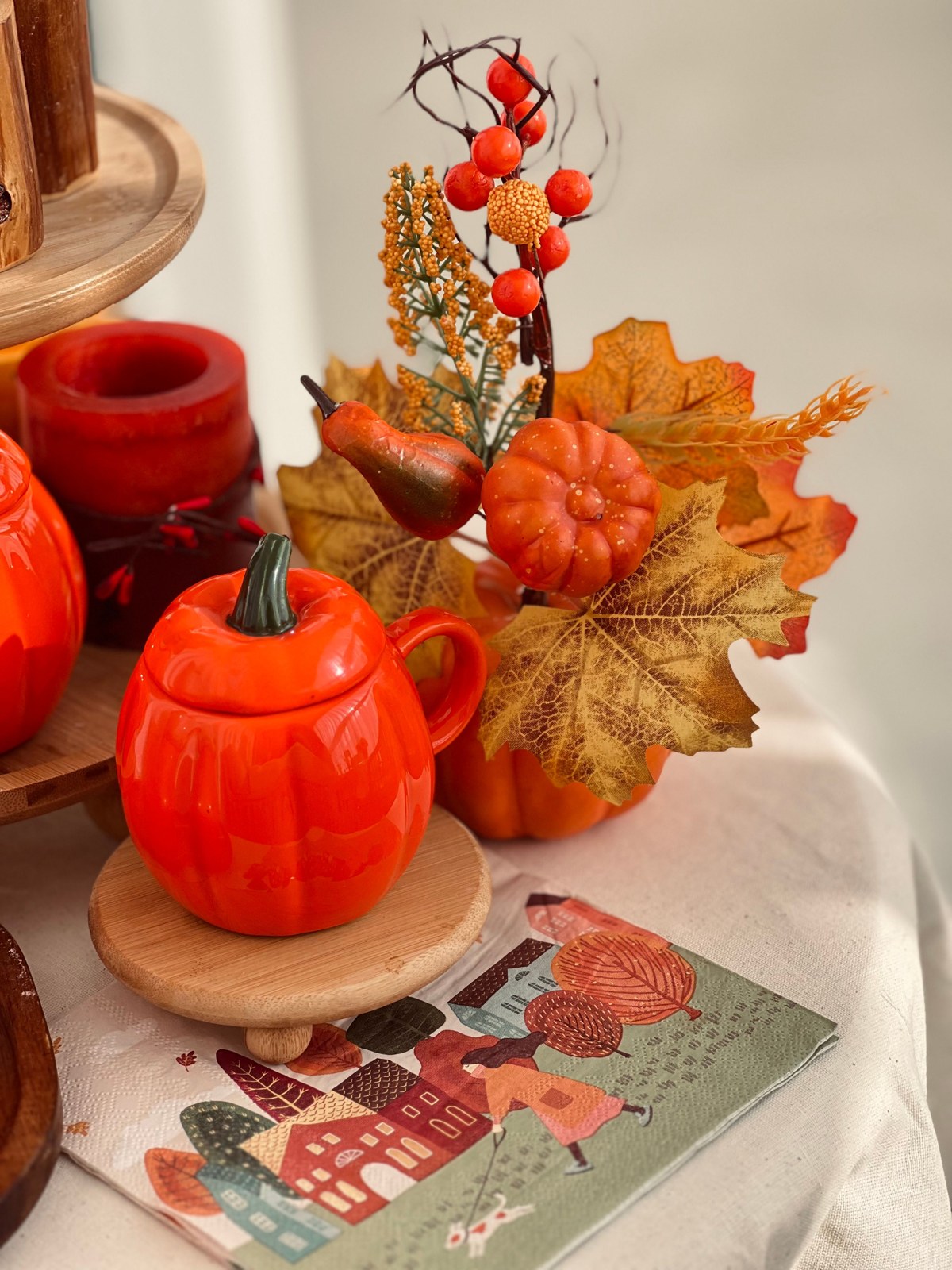 Orange pumpkin decorations, fall leaves, and a patterned napkin on a seasonal table
