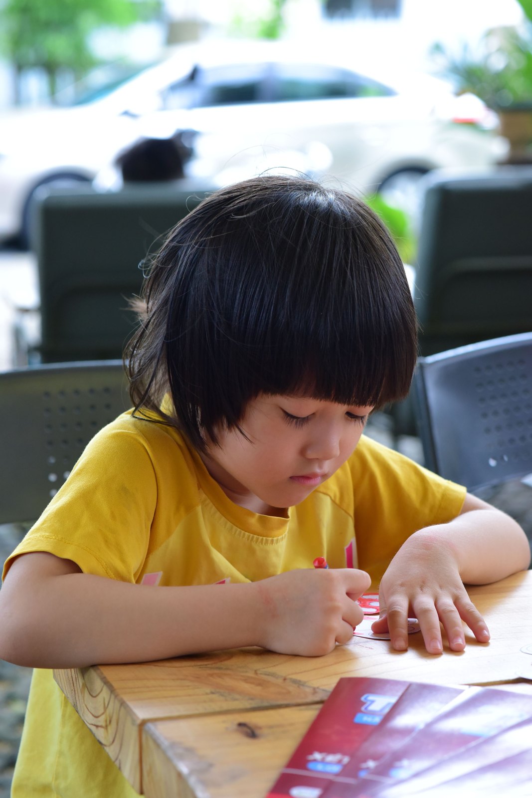 A child drawing on paper at an outdoor table