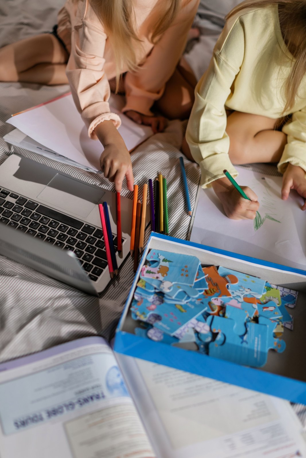 Two children drawing on paper with colored pencils at home