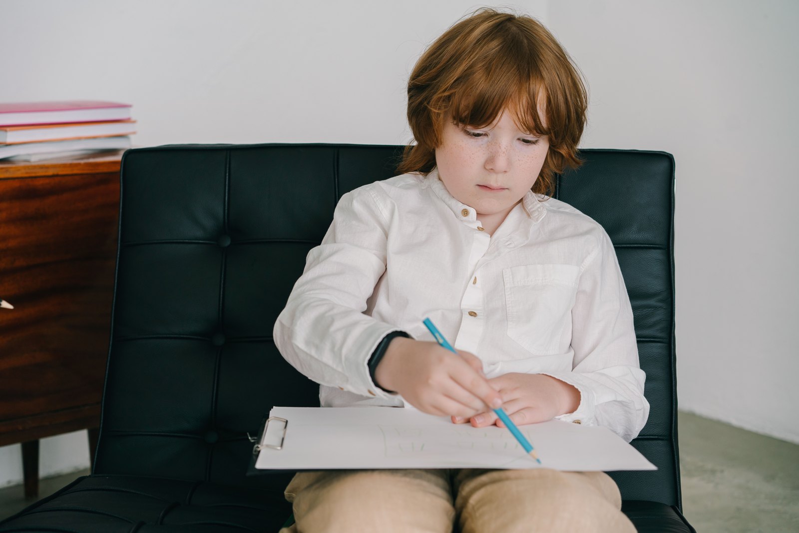 A child drawing with colored pencils on a board resting on their lap