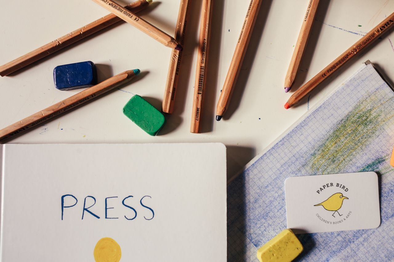 Colored pencils, erasers, and paper arranged for a drawing project.