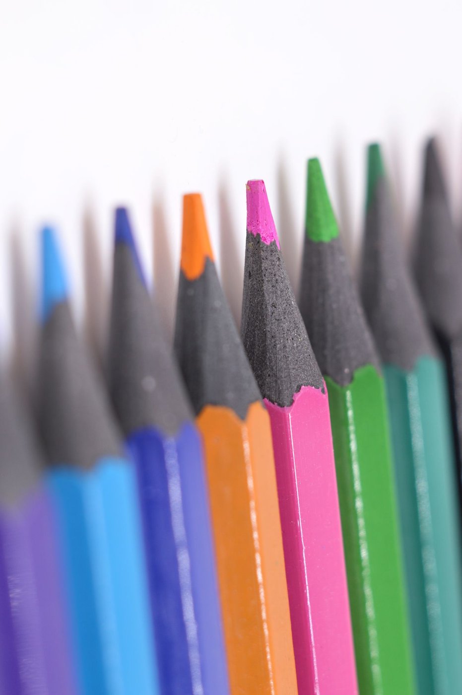 Colored pencils arranged in a row on a white surface.