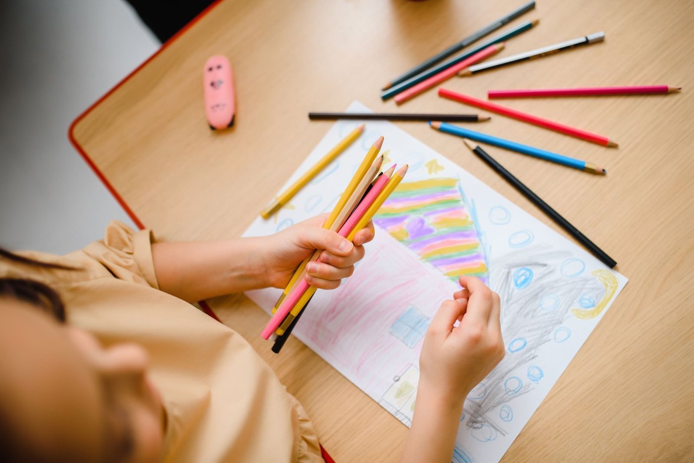 A child drawing with colored pencils on paper at a table