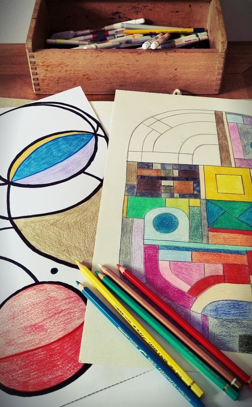 Colored pencils resting on a drawing with geometric color patterns